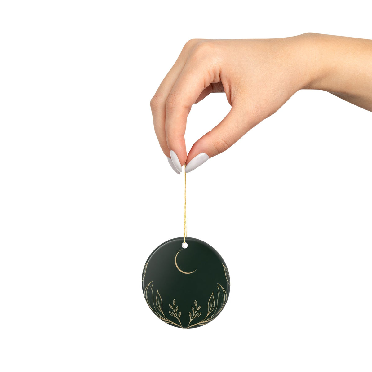 Hand holding the circle ornament by its gold cord, showing its size