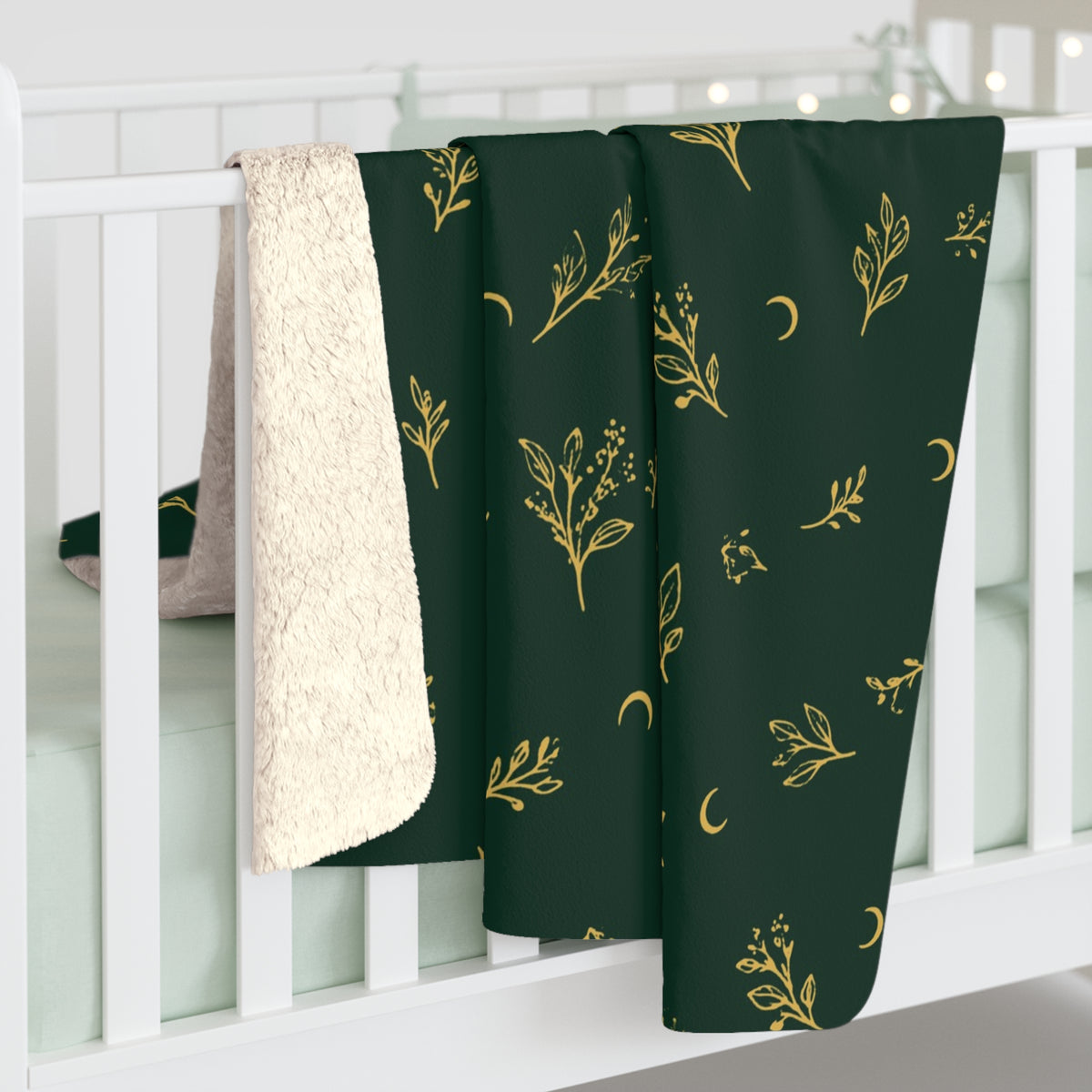 Botanical Gold sherpa blanket hanging over a crib rail, cream sherpa back showing