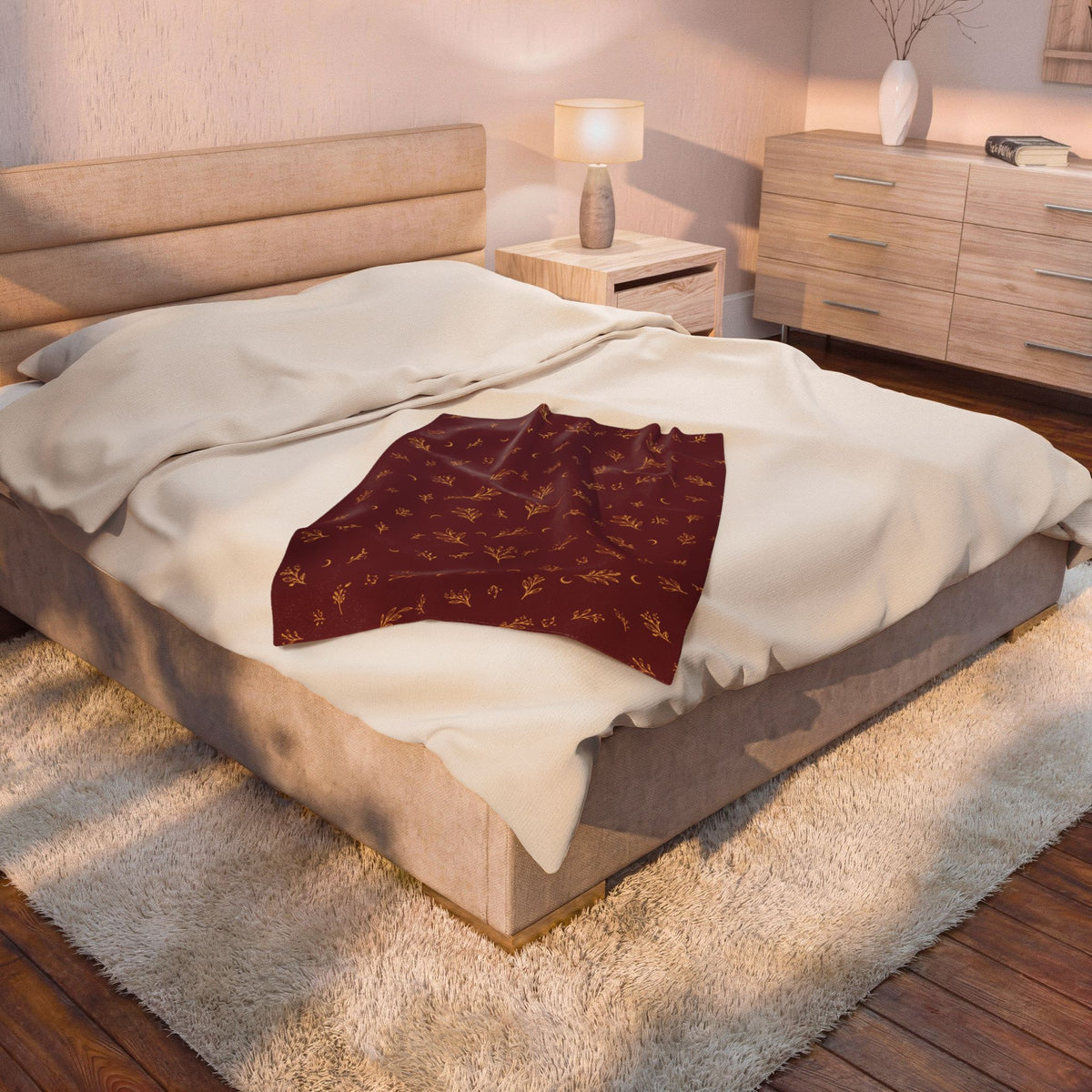 Cranberry Gold plush blanket on a bed beside a bedside lamp