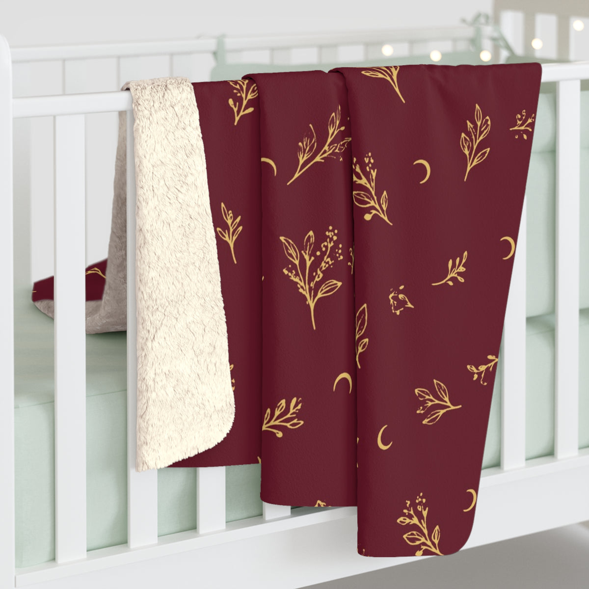 Cranberry Gold sherpa blanket hanging over a crib rail, cream sherpa back showing