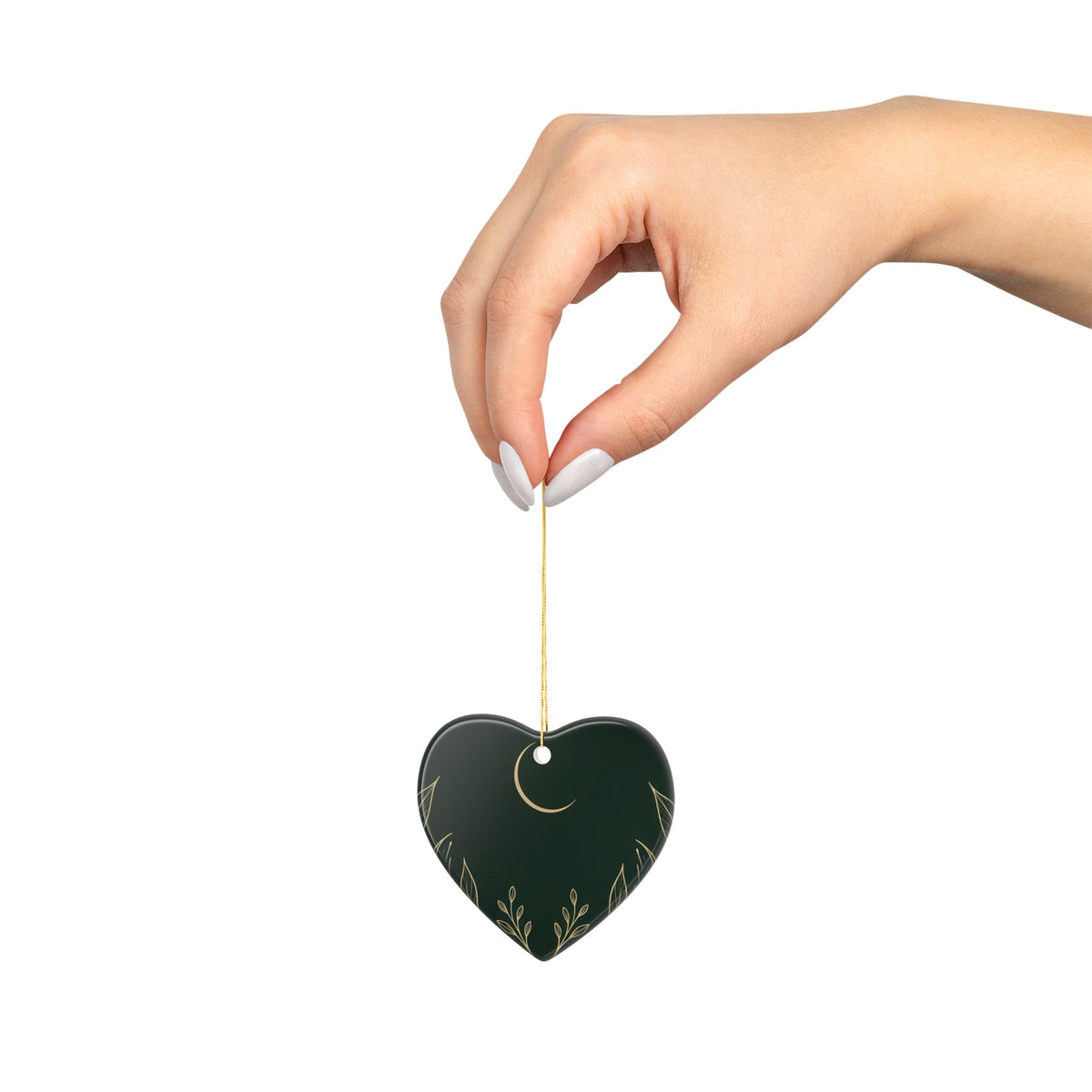 Hand holding the heart ornament by its gold cord, showing its size