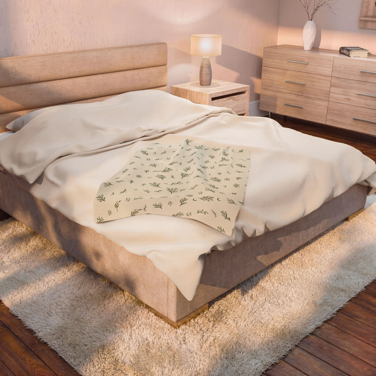 Cream Sage plush blanket on a bed beside a bedside lamp