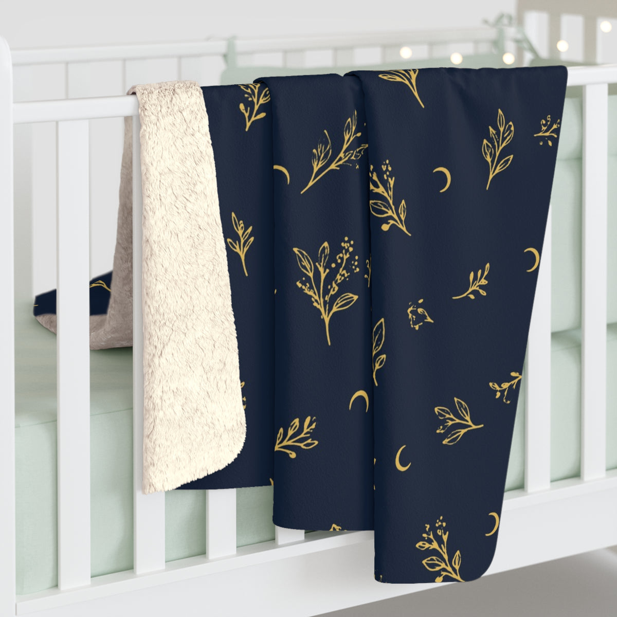 Navy Gold sherpa blanket hanging over a crib rail, cream sherpa back showing