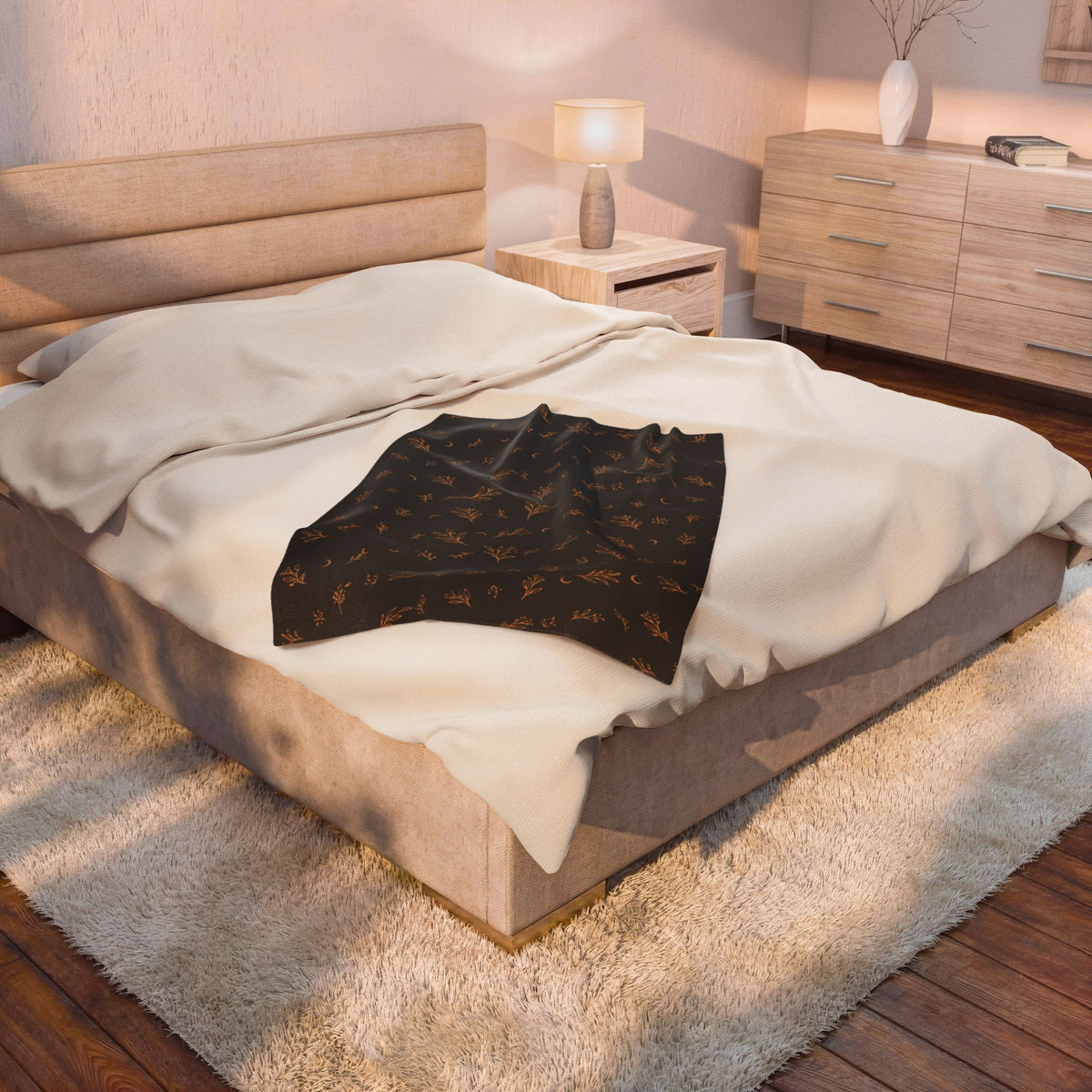 Charcoal Copper plush blanket on a bed beside a bedside lamp
