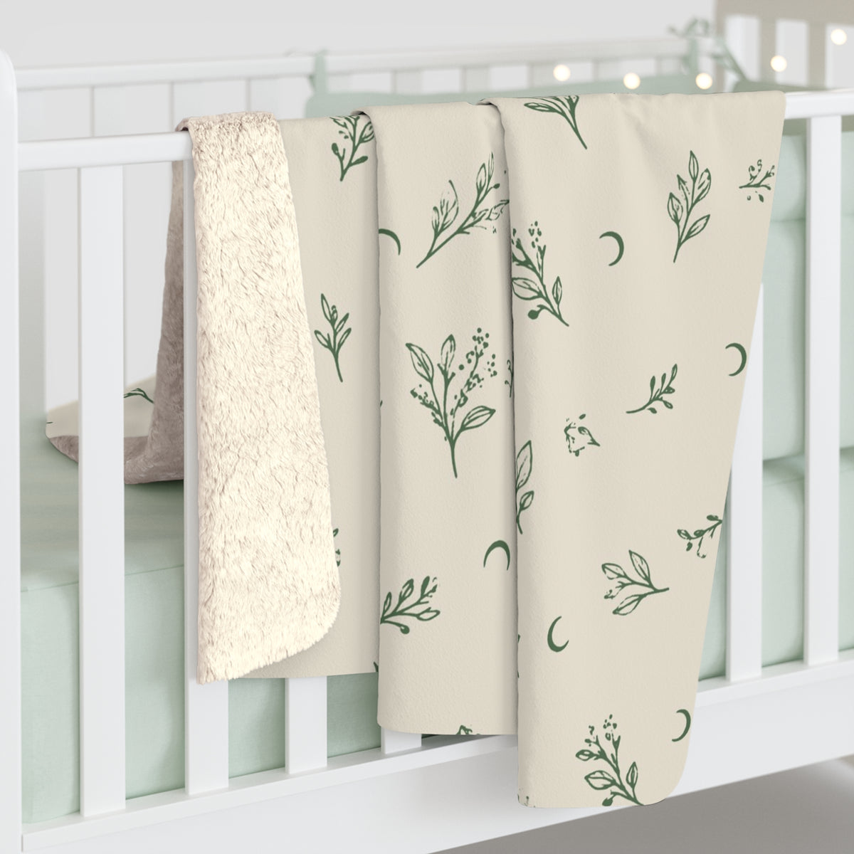 Cream Sage sherpa blanket hanging over a crib rail, cream sherpa back showing