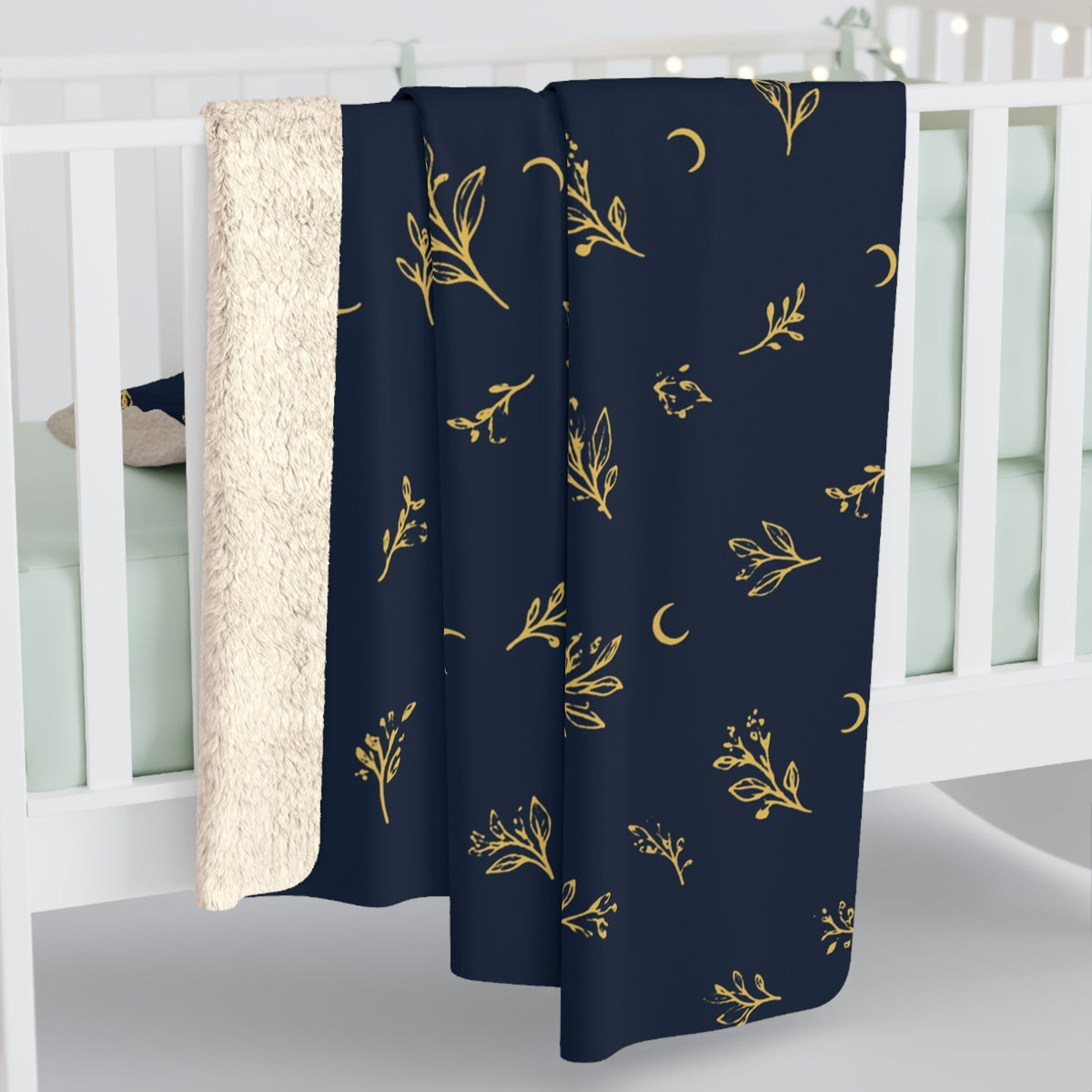 Navy Gold sherpa blanket hanging over a crib rail, cream sherpa back showing (larger size)