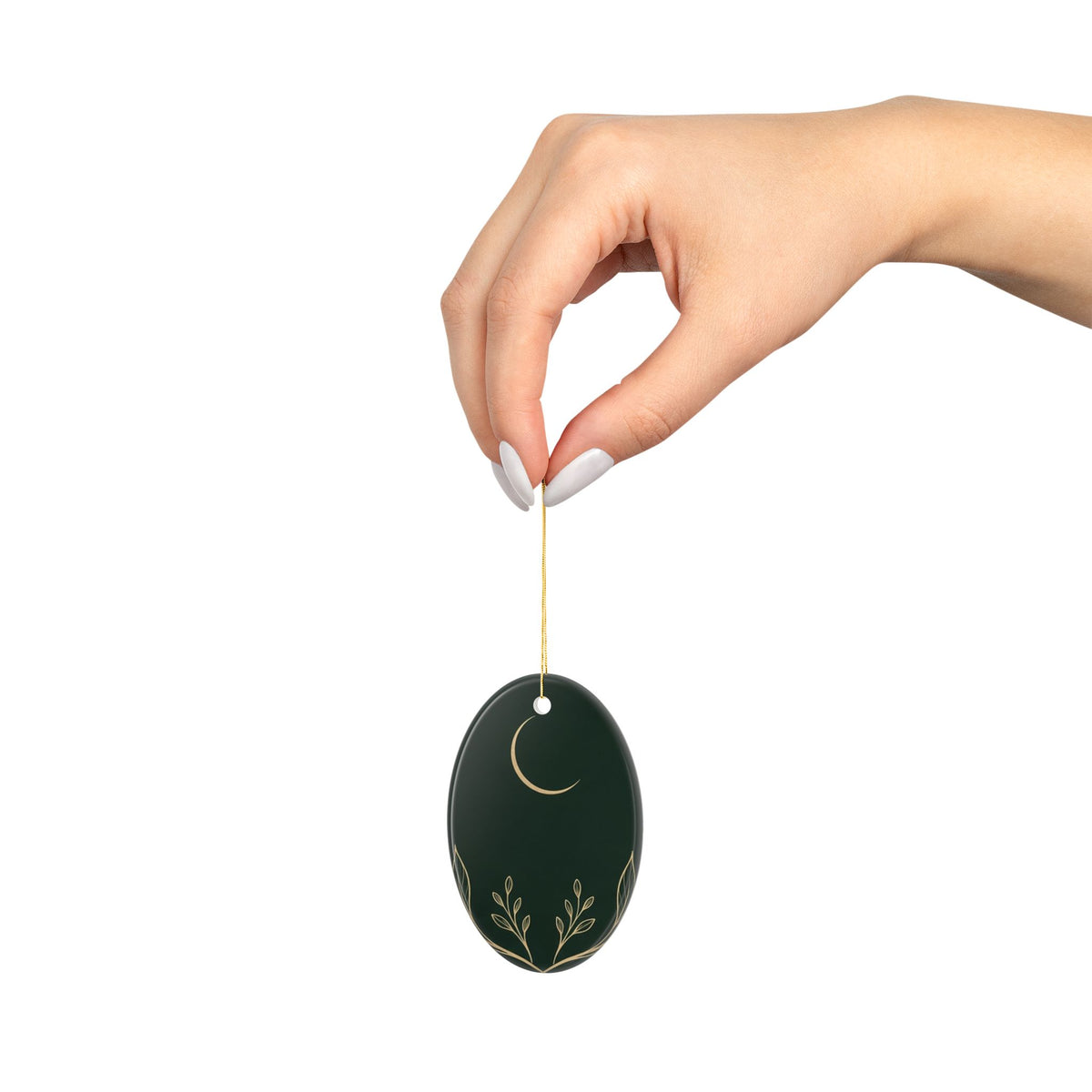 Hand holding the oval ornament by its gold cord, showing its size