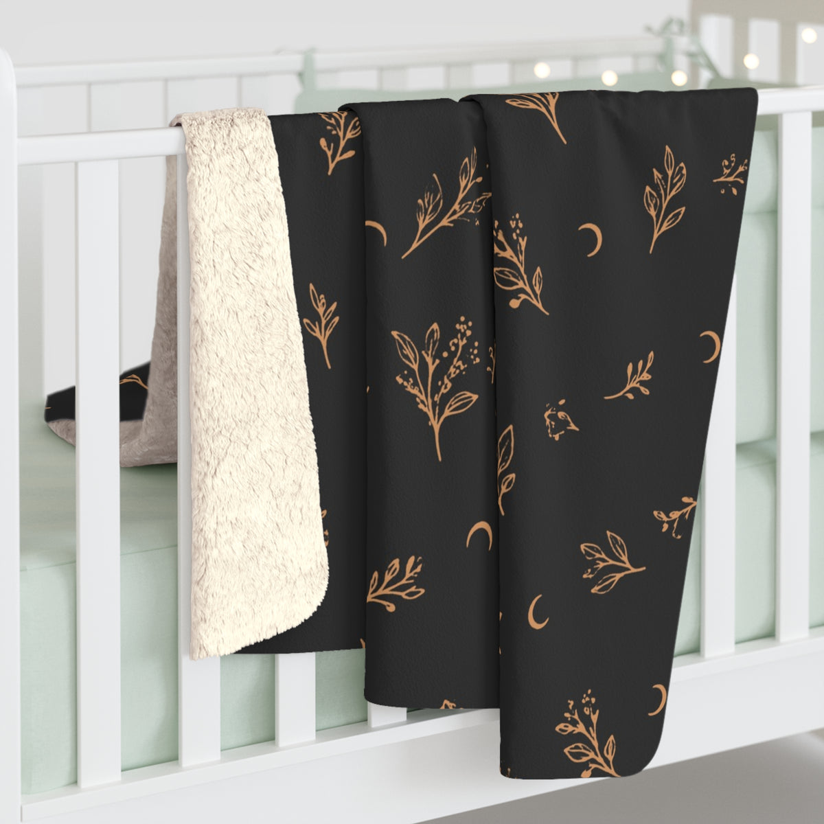 Charcoal Copper sherpa blanket hanging over a crib rail, cream sherpa back showing